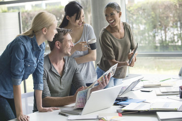 Colleagues chatting while browsing color swatch catalog