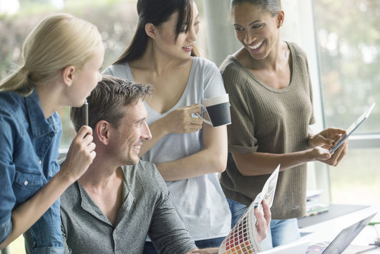 Colleagues having lighthearted time while browsing color swatch catalog