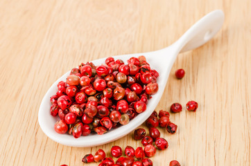 pink peppercorns in white spoon.