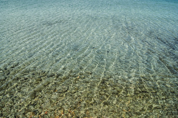 Azure water with green pebbles at the beach