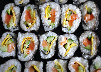 Homemade rolls made of rice, salmon, scrambled eggs and cucumber closeup. Selective focus, top view.