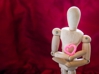 Still life wooden puppet and pink heart.