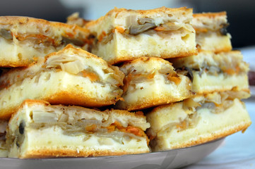 Pieces of sliced homemade pie with cabbage and carrot, stacked on each other closeup.