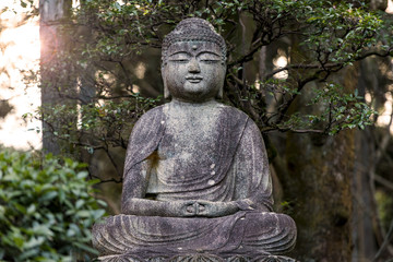 Fototapeta na wymiar Old stone Buddha - statue at a park