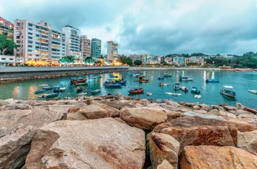 Foto op Canvas Rocky sea shore of Stanley Bay on Hong Kong Island in Hong Kong. Beautiful scenic landscape with water, mountains, rocks, buildings, fishing boats and cloudy sky © Wilding