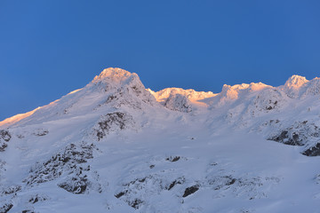 Beautiful view of mountain peak with sunset light on top against clear blue sky