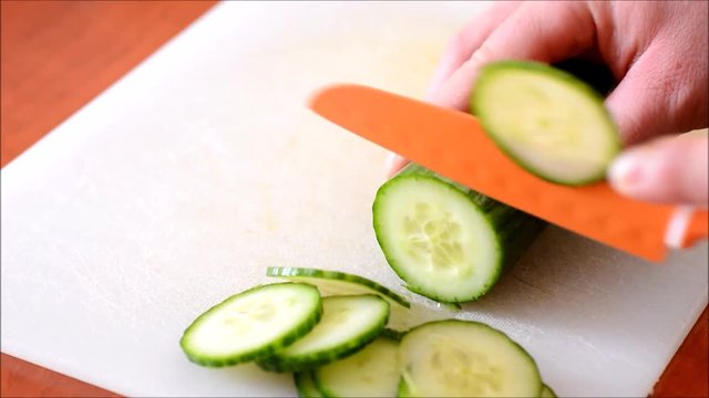 Chopping the fresh cucumber into small slices on chopping board time lapse.