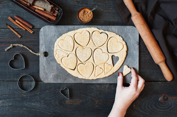 Female hands cut the cookies-hearts from the dough