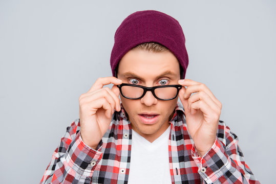 Portrait of shocked young man in hat and glasses with open mouth