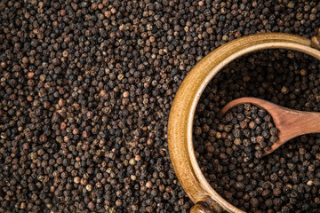 Black pepper grain in the bowl on the pepper background. Healthy eating and lifestyle.