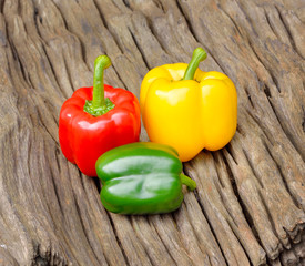 Green , yellow and red bell pepper on wood background