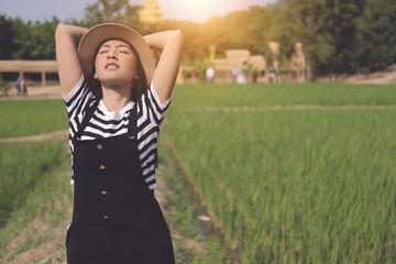 Woman stand breathing deep fresh air in a rice green wheat field wearing a black shirt