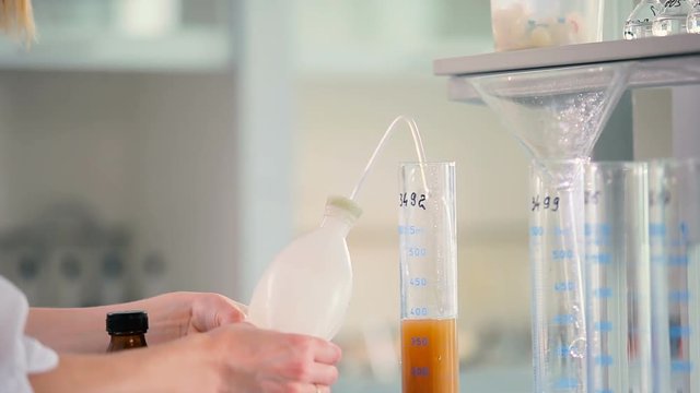 Woman transposes the funnel to the other beaker.