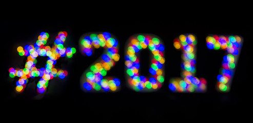Hashtag 2017 message formed with colorful bokeh lights on black background