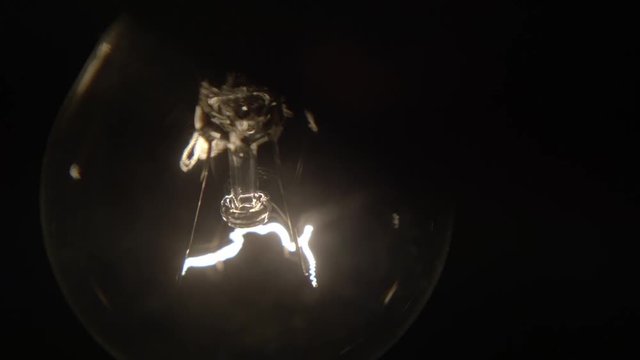 Flashing lamp bulb; light glowing incandescent filament . Detail of incandescent filament of a traditional bulb on the dark