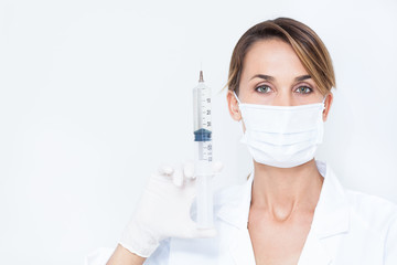 portrait d'une femme médecin avec un masque et une grosse seringue