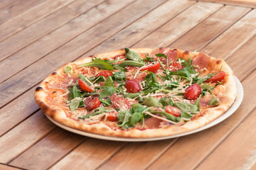 pizza on a wooden table with tomato and cheese
