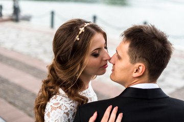 happy bride and groom at a park on their wedding day sitting on a bench near the lake
