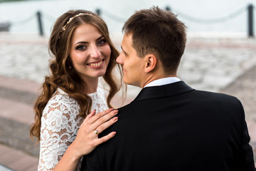happy bride and groom at a park on their wedding day sitting on a bench near the lake