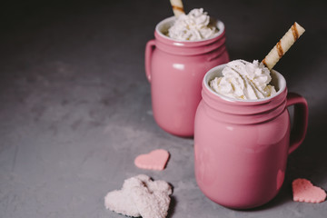 Two pink mugs with hot chocolate and cream on a gray concrete background. Drinks for a loving couple. The concept of Valentine's Day.