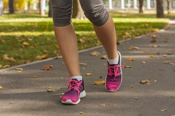 Fototapeta na wymiar Runner woman feet running on road closeup on shoe. Fitness woman in training shoes jogging outdoors in park. Sport active lifestyle 