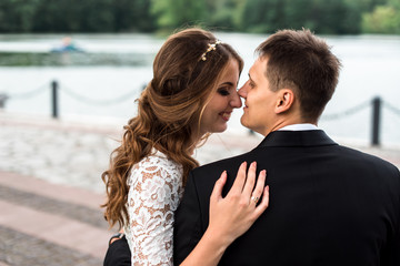 happy bride and groom at a park on their wedding day sitting on a bench near the lake