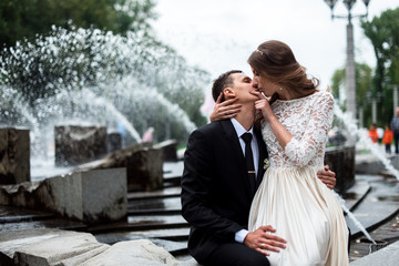 Naklejka premium Bride and groom kissing with the fountain on the background