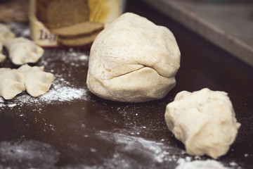 Raw dough for dumplings at wooden brown table