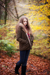 Young teenage girl standing in a forrest in Autumn