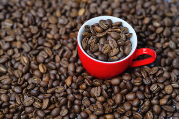 Red cup full of coffee beans on coffee background