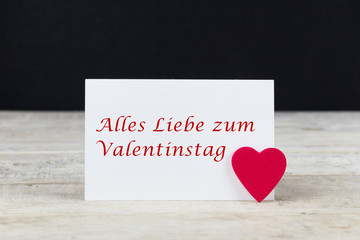 Valentine greeting card on wooden table with text " Alles Liebe zum Valentinstag", written in German, which means " Happy Valentine's day" in English.