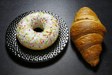 donut with colorful topping and croissant on black background