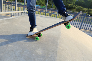 young skateboarder legs riding skateboard at skatepark