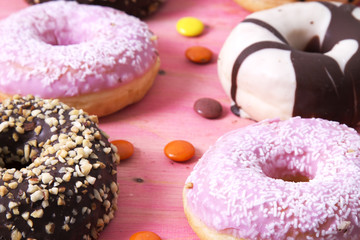 assortment of donuts and candies on pink wooden background