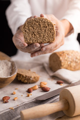 A male chef's hand present and cutting whole grain bread with gold knife and pouring flour.