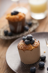 Blueberry muffin in a dish decorated with fresh blueberry and white candle on the table