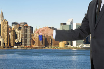 Man holding out a car key with business background	