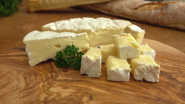 Soft brie cheese cubes on rustic wooden board
