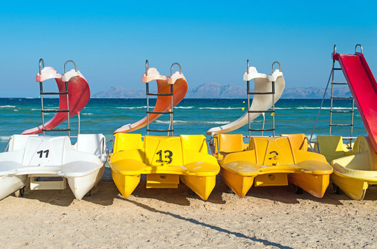 Pedal-boats with water slides on the beach.