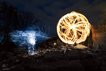 Man is spinning the poi with fire and making different shapes at night
