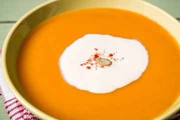 Pumpkin soup on green rustic wooden background