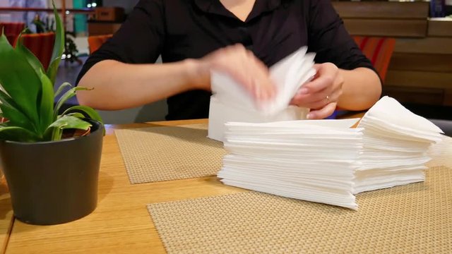Female hands folding a lot of napkins.
