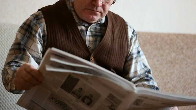 Old man reading the newspaper at home.