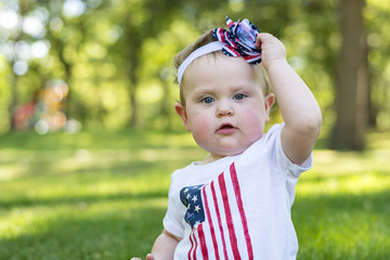 Festive one year old girl in the park on the 4th of July