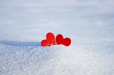 Fototapeta premium two red paper heart stand side by side in the snow