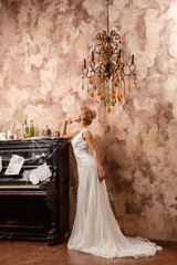 Beautiful sexy blonde in dress posing in a castle by the Christmas tree and piano
