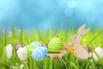Easter rabbit with eggs in cart in the green grass with blue sky