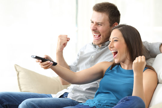 Excited couple watching tv on couch