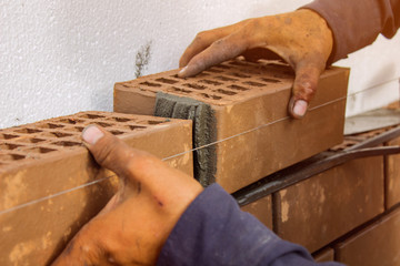 Bricklayer lays bricks under unravel. construction work