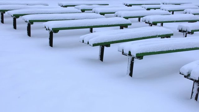 Wooden Benches in a Park Covered Completely by Snow After Heavy Snowfall. Snow depositing on the benches in the park after a snowfall.